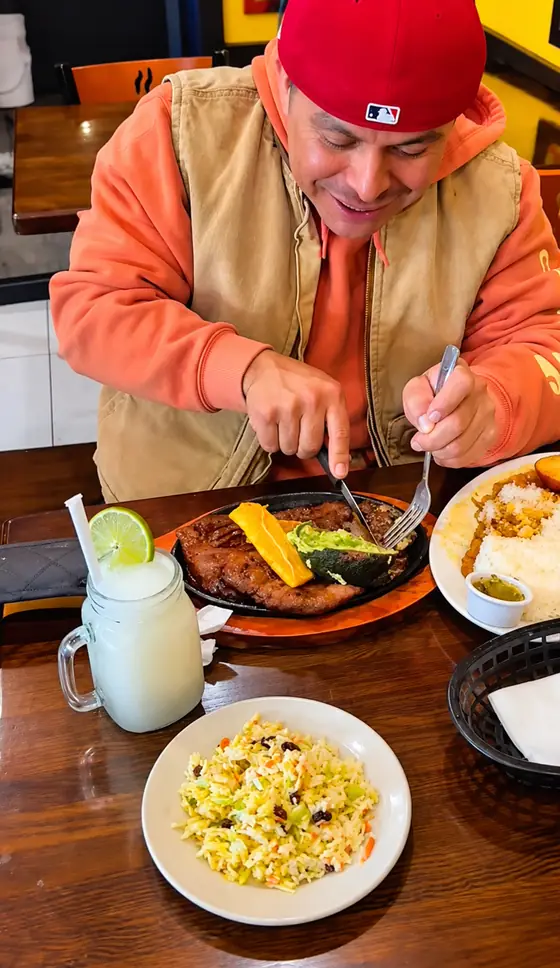 Customer eating churrasco with fresh lemonade at El Rinconcito Paisa 2